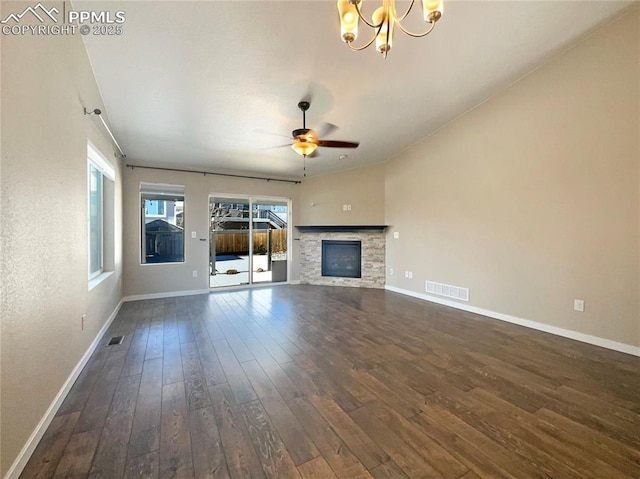 unfurnished living room featuring dark hardwood / wood-style flooring, a stone fireplace, and ceiling fan with notable chandelier