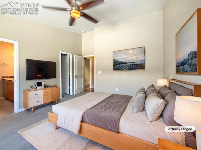 carpeted bedroom with ceiling fan and ensuite bath