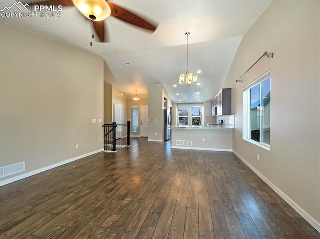 unfurnished living room with dark wood-type flooring, lofted ceiling, and ceiling fan with notable chandelier