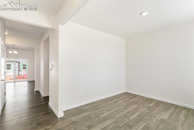 empty room featuring a notable chandelier and dark hardwood / wood-style floors