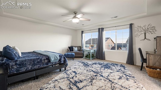 carpeted bedroom featuring a raised ceiling and ceiling fan