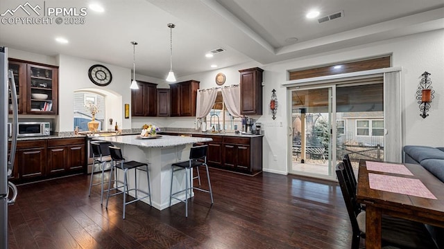 kitchen with sink, a center island, hanging light fixtures, appliances with stainless steel finishes, and dark hardwood / wood-style flooring