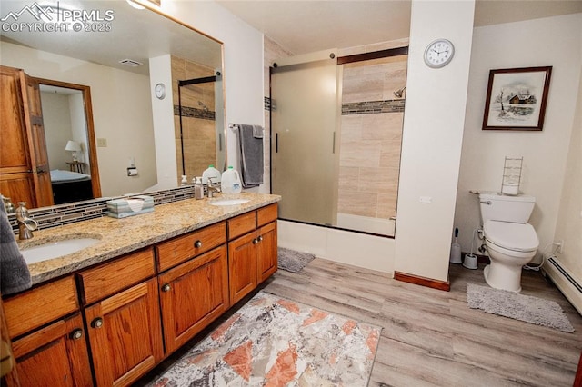 full bathroom featuring shower / bath combination with glass door, baseboard heating, vanity, wood-type flooring, and toilet