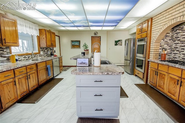 kitchen with appliances with stainless steel finishes, sink, a kitchen island with sink, and decorative backsplash