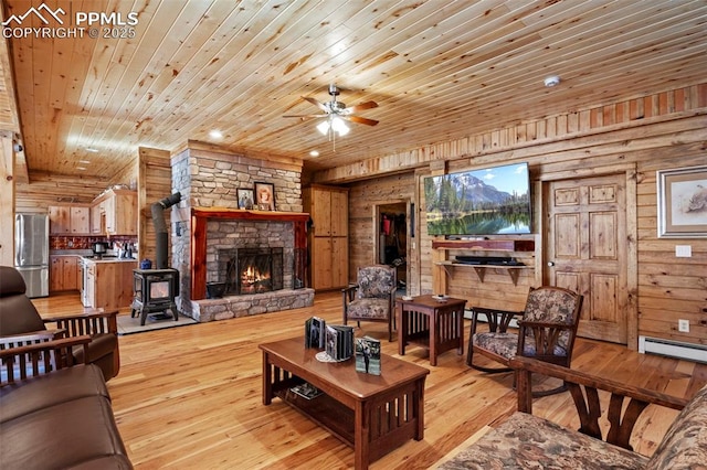 living room with wood ceiling, wooden walls, light hardwood / wood-style floors, and a wood stove