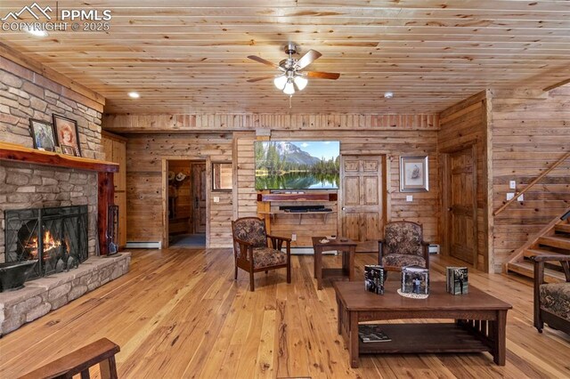 living room featuring a stone fireplace, wooden ceiling, baseboard heating, and light hardwood / wood-style flooring