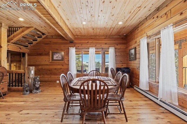 dining space featuring baseboard heating, wood ceiling, wooden walls, and light hardwood / wood-style flooring