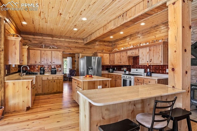 kitchen with sink, stainless steel fridge, a center island, kitchen peninsula, and white gas stove