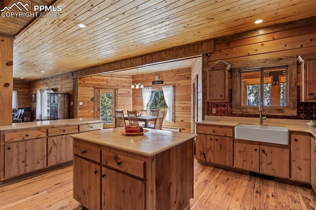 kitchen featuring sink, light hardwood / wood-style flooring, wooden ceiling, and a center island