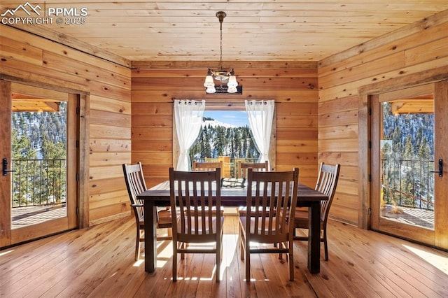 dining room with wooden ceiling, wood walls, and light hardwood / wood-style flooring