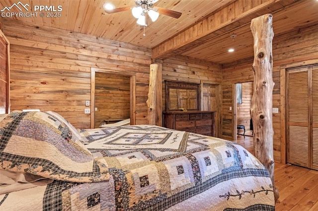 bedroom with hardwood / wood-style floors, wooden ceiling, ceiling fan, and wood walls