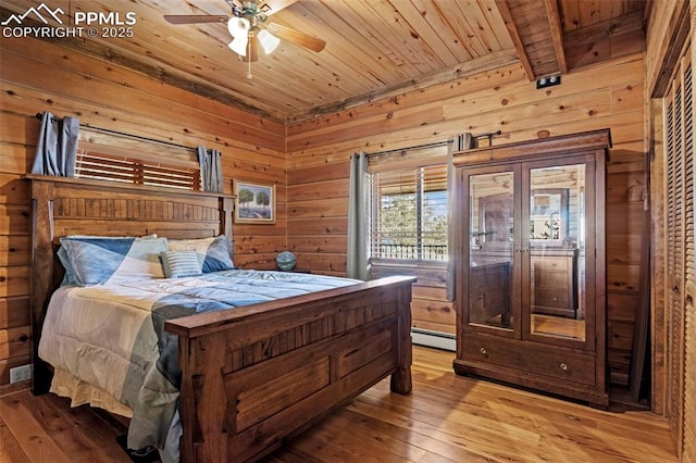 bedroom featuring hardwood / wood-style flooring, ceiling fan, wooden walls, a baseboard radiator, and wooden ceiling