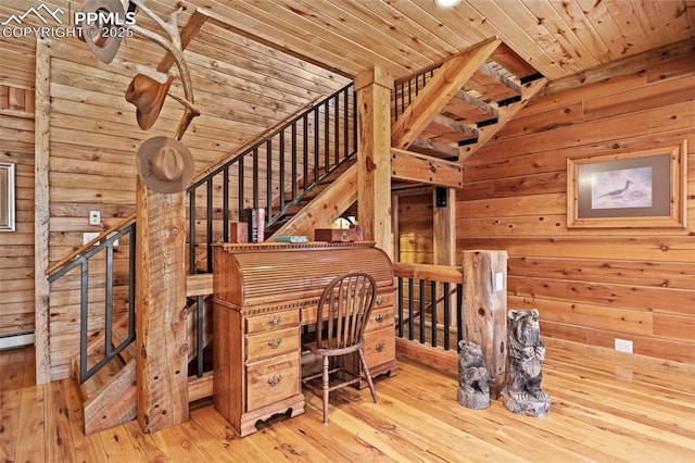 unfurnished office with wood ceiling, wooden walls, and light wood-type flooring