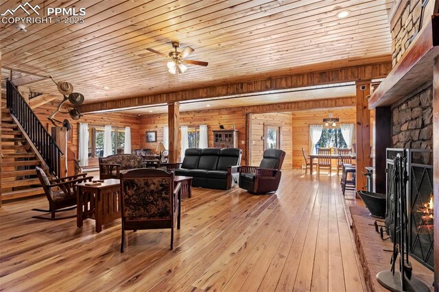 living room with a stone fireplace, wood walls, wood ceiling, light hardwood / wood-style flooring, and ceiling fan