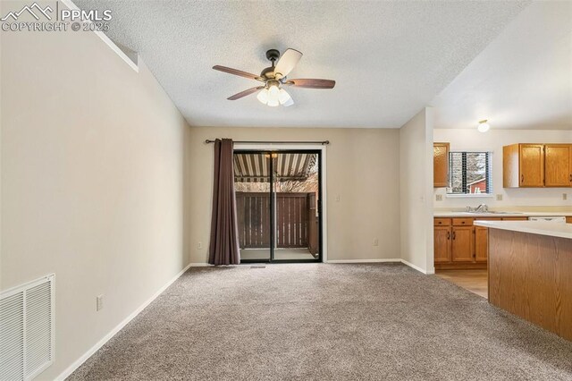 unfurnished living room with ceiling fan, sink, light carpet, and a textured ceiling