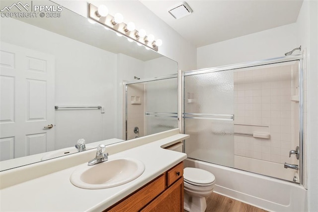 full bathroom featuring enclosed tub / shower combo, wood-type flooring, toilet, and vanity