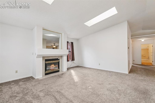 unfurnished living room with vaulted ceiling, a tile fireplace, and carpet