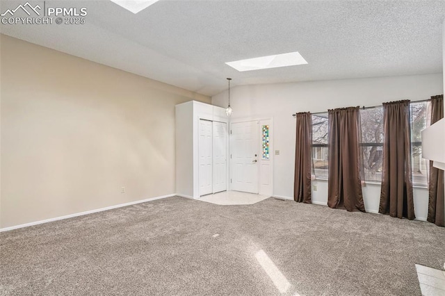 carpeted empty room featuring vaulted ceiling with skylight and a textured ceiling