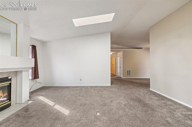 unfurnished living room with light colored carpet, a fireplace, and a skylight