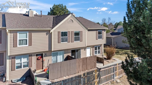 view of front of home featuring roof with shingles, fence, and a chimney