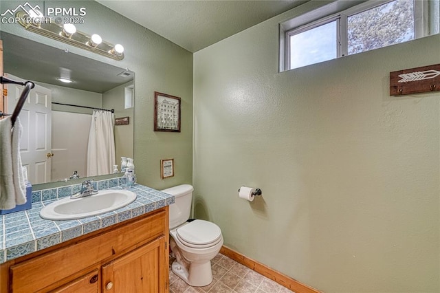 bathroom featuring toilet, vanity, baseboards, a shower with curtain, and tile patterned floors