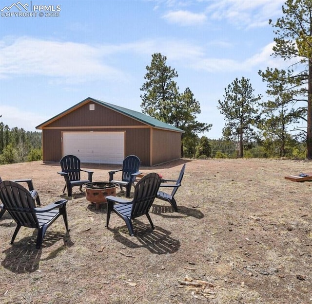 view of yard featuring a garage, an outdoor fire pit, and an outdoor structure