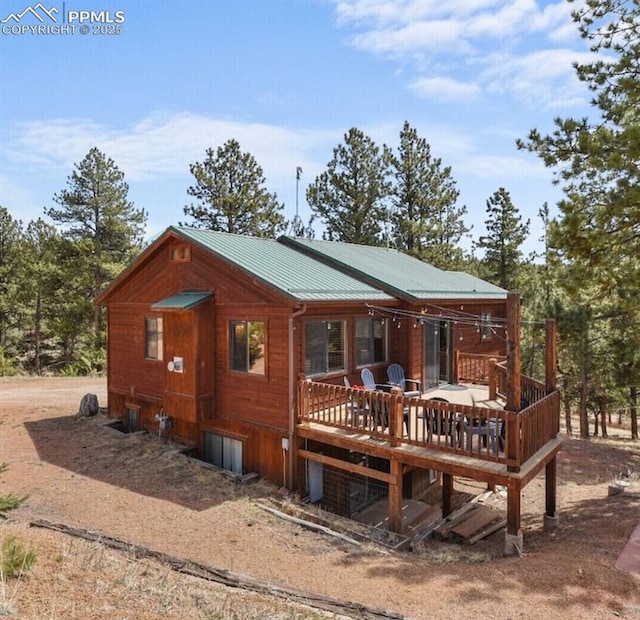 exterior space featuring metal roof, a deck, and dirt driveway