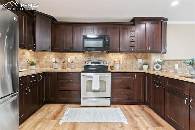 kitchen with light wood-type flooring, dark brown cabinets, light stone countertops, and stainless steel appliances