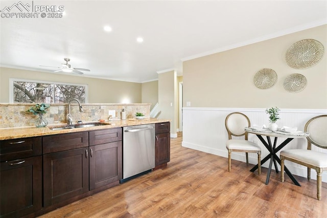 kitchen with dark brown cabinets, light wood-type flooring, stainless steel dishwasher, ornamental molding, and sink