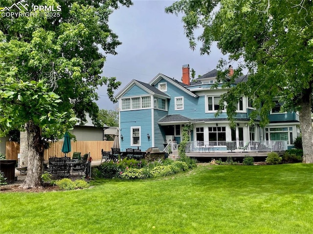 rear view of property featuring a yard, a patio, and a deck