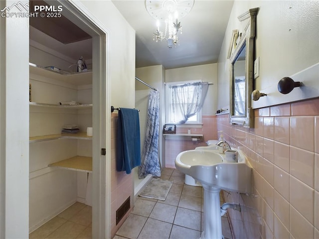 bathroom with tile walls, tile patterned floors, an inviting chandelier, and a shower with shower curtain