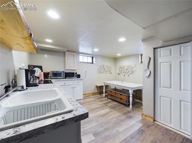 kitchen with white cabinetry, sink, and light hardwood / wood-style flooring