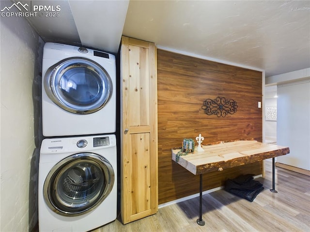 laundry room featuring stacked washer / dryer and wood-type flooring