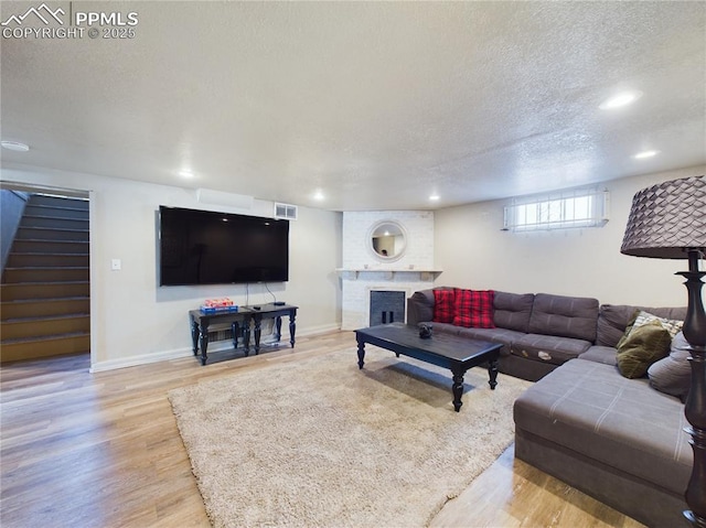 living room featuring a brick fireplace, light hardwood / wood-style flooring, and a textured ceiling