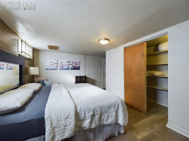 bedroom with a closet, dark hardwood / wood-style flooring, and a textured ceiling