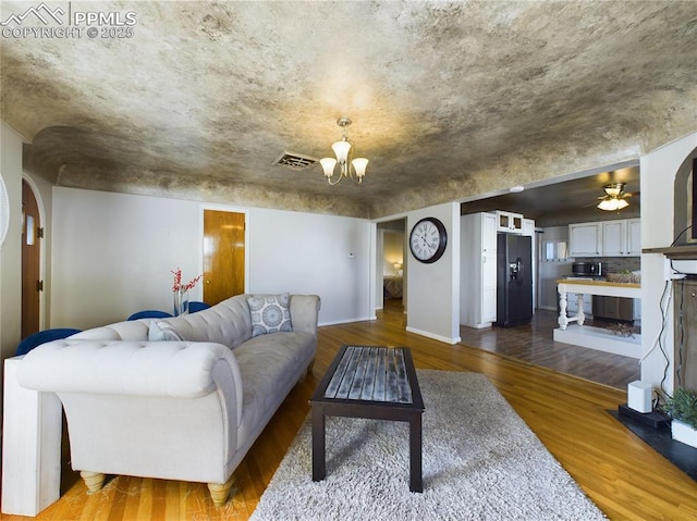 living room featuring wood-type flooring and ceiling fan with notable chandelier