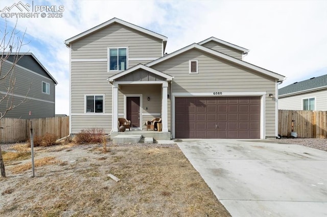 traditional home featuring a garage, concrete driveway, and fence