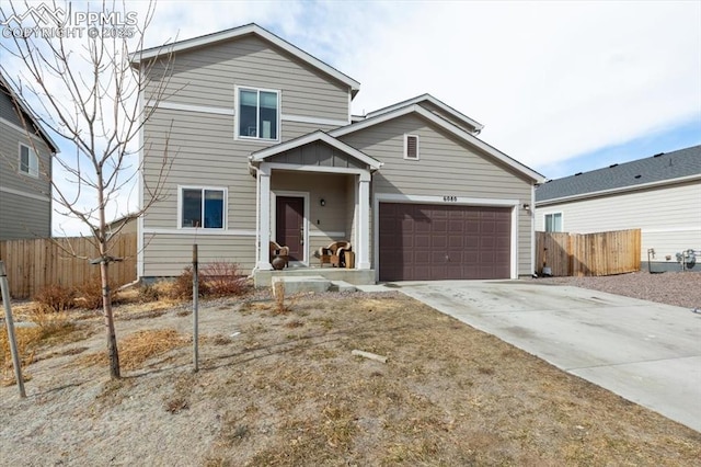 traditional home with a garage, concrete driveway, and fence