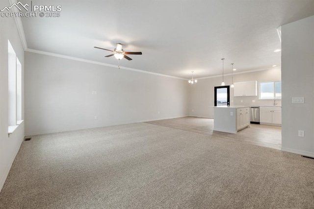 unfurnished living room with crown molding, ceiling fan with notable chandelier, and light carpet