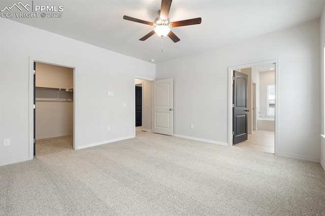 unfurnished bedroom featuring connected bathroom, a walk in closet, ceiling fan, light carpet, and a closet