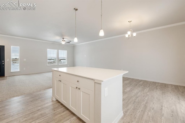 kitchen featuring a kitchen island, white cabinetry, hanging light fixtures, light hardwood / wood-style floors, and crown molding