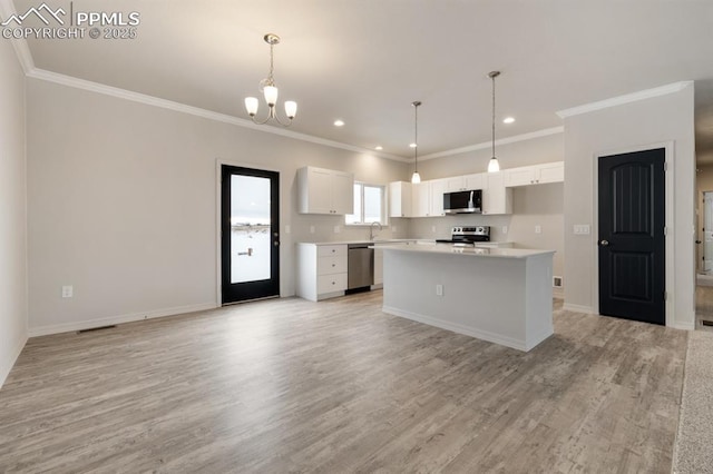 kitchen featuring sink, stainless steel appliances, a center island, white cabinets, and decorative light fixtures