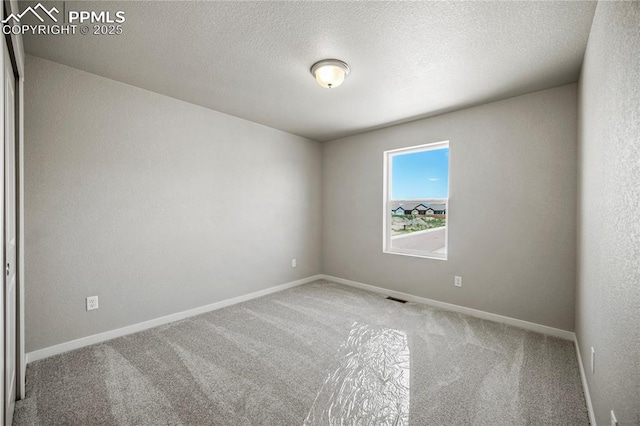 carpeted empty room featuring a textured ceiling