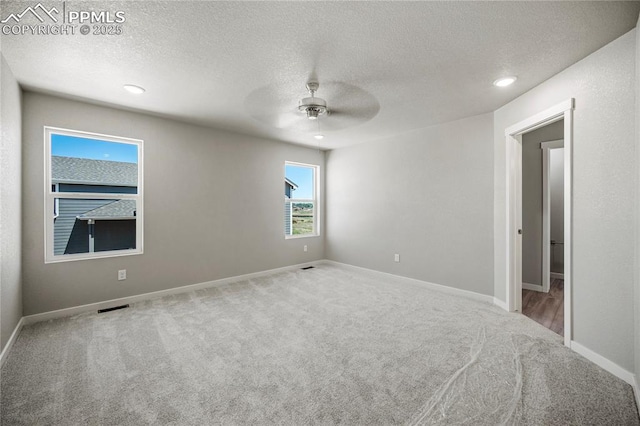 unfurnished room featuring ceiling fan, light colored carpet, and a textured ceiling