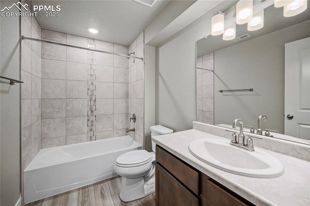 full bathroom featuring vanity, wood-type flooring, toilet, and tiled shower / bath