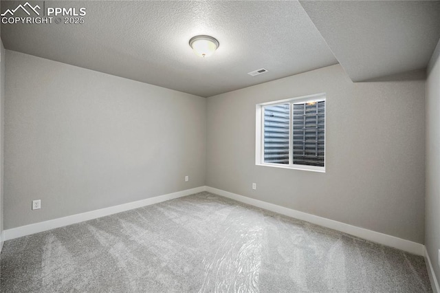 empty room with carpet floors and a textured ceiling