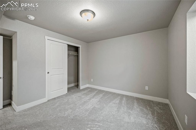 unfurnished bedroom with light carpet, a closet, and a textured ceiling