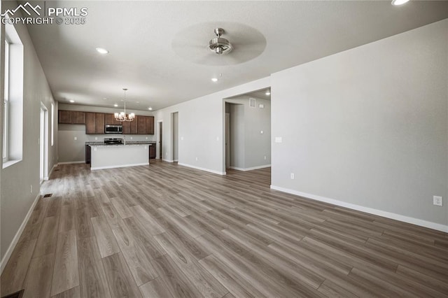 unfurnished living room with hardwood / wood-style flooring and ceiling fan with notable chandelier