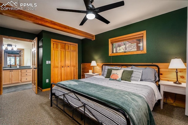 bedroom featuring ceiling fan, beam ceiling, dark carpet, and a closet