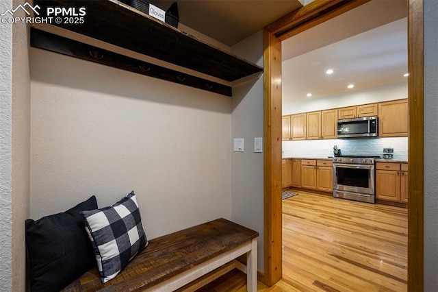 kitchen with tasteful backsplash, light brown cabinetry, light hardwood / wood-style flooring, and stainless steel appliances